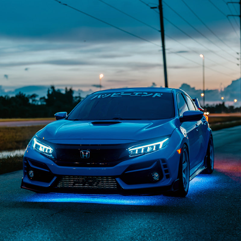 Blue Honda Civic on a road at dusk with city lights in the background