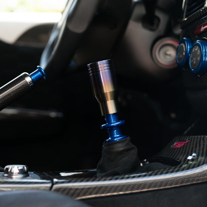 Close-up of a car gear shift lever with a blue accent inside a vehicle.