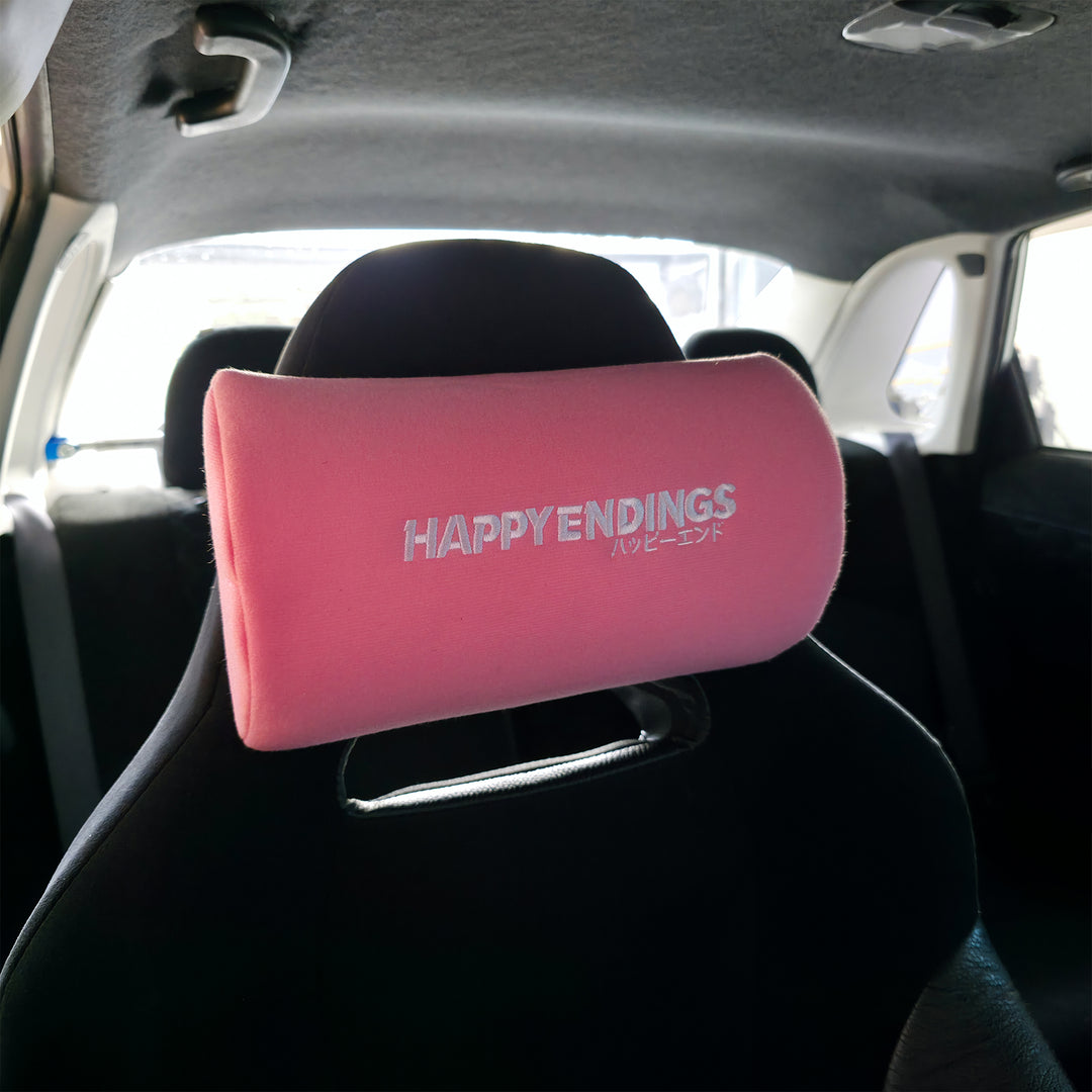 Baby Pink neck pillow with 'HAPPY ENDINGS' text in a car interior