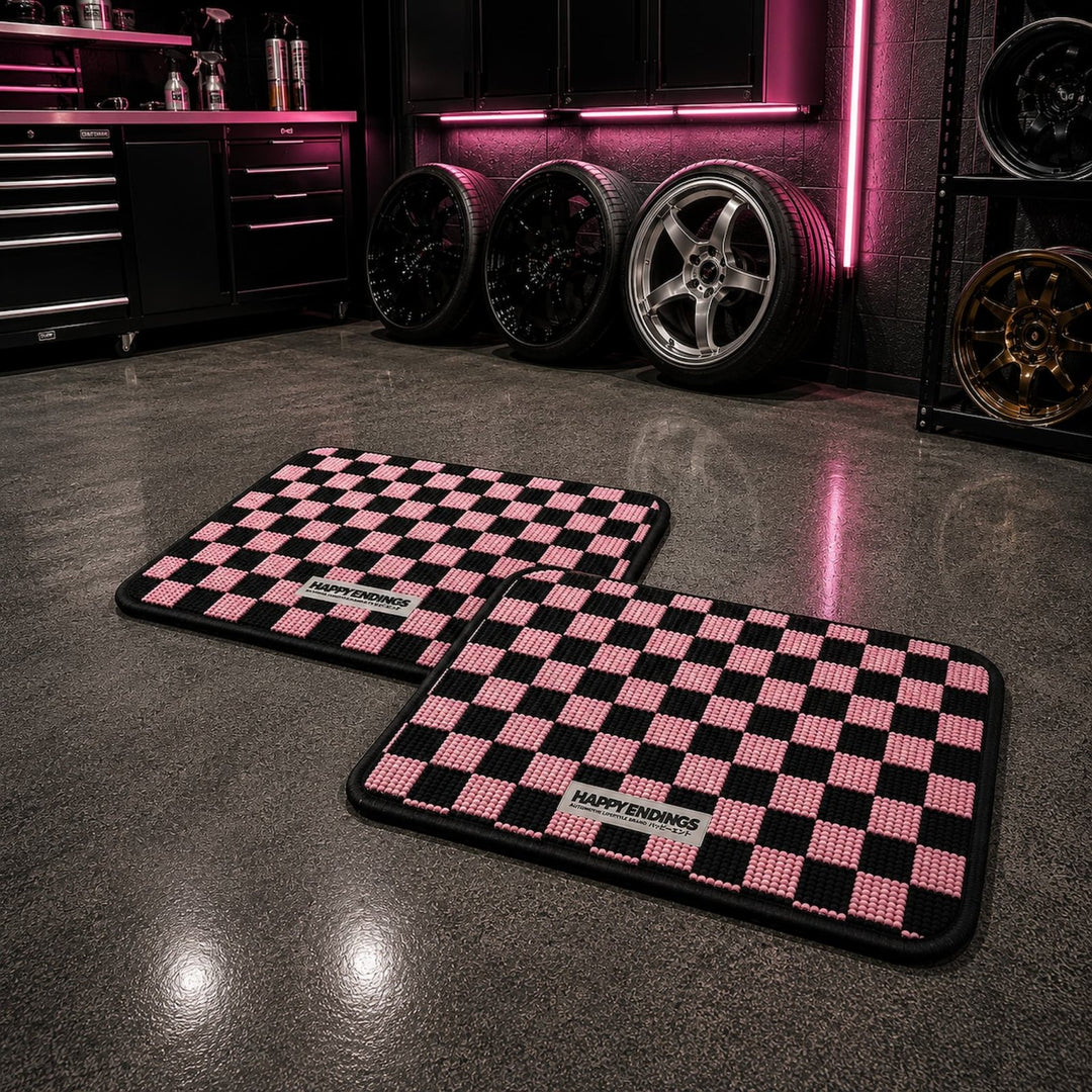 Two pink and black checkered mats on a shiny garage floor, with rims and neon...