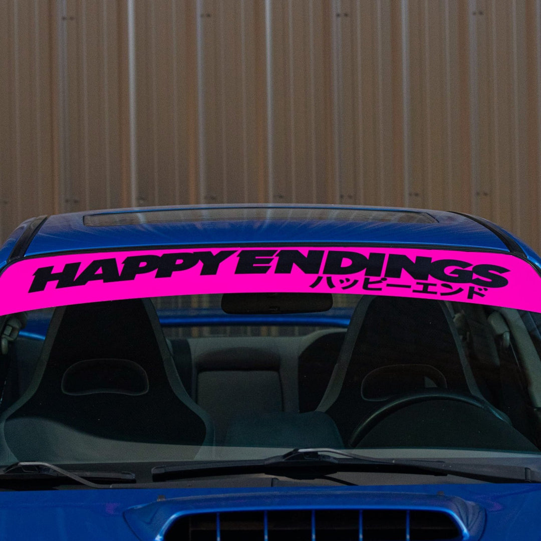 A blue car with a bright pink windshield banner reading HAPPY ENDINGS and Japanese text.