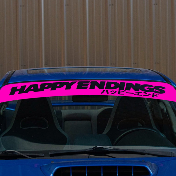 A blue car with a bright pink windshield banner reading HAPPY ENDINGS and Japanese text.
