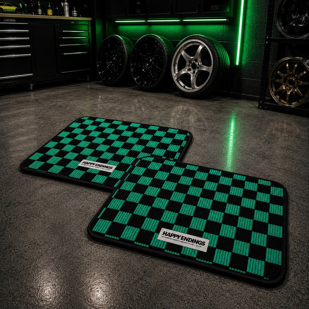 Two green and black checkered mats labeled Happy Endings on a garage floor wi...