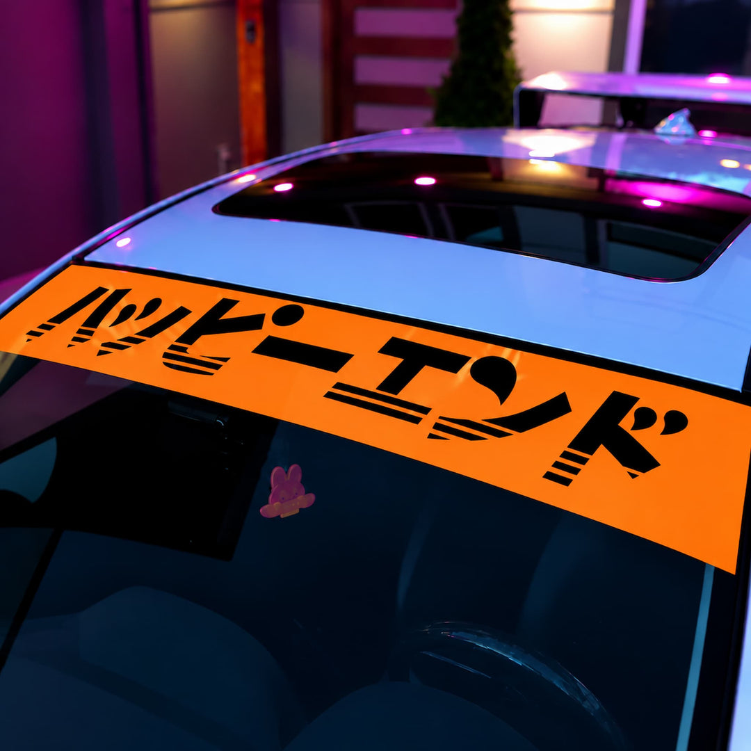 Orange windshield banner with Japanese text reading Happy End on a white car.