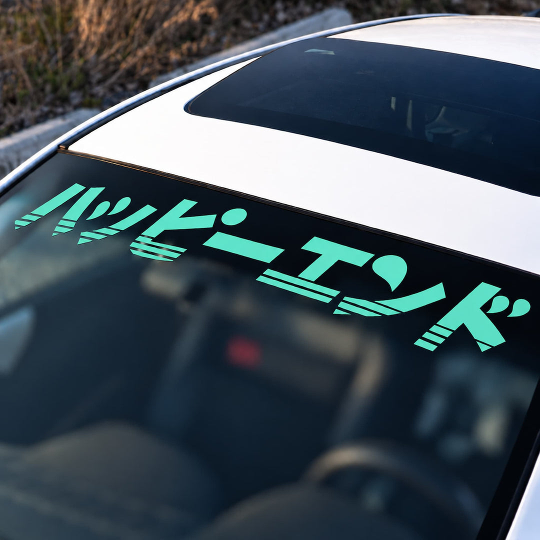 Light blue Japanese text reading Happy End on a car windshield banner.