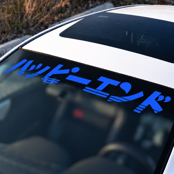 Blue Japanese text sticker on the top of a car windshield.