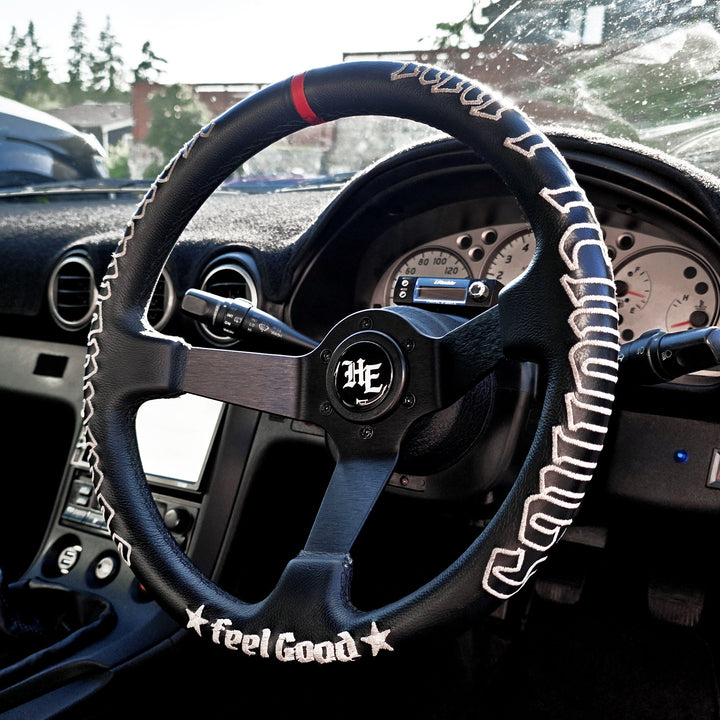 Black deep-dish steering wheel with white embroidered stitching, matte black 3-spoke design.