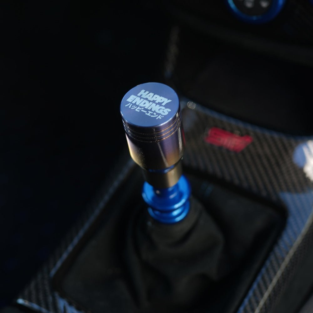 Close-up of a car gear shift knob with 'Happy Tunings' branding.