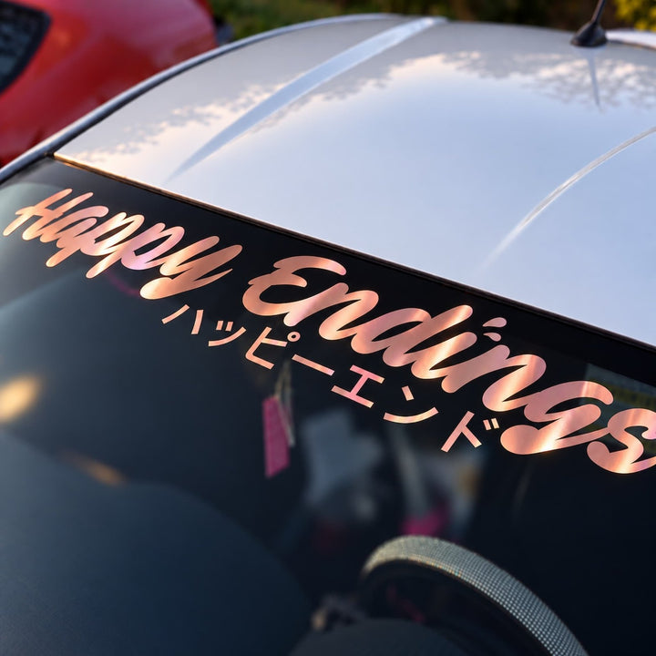 Car windshield sticker reading Happy Endings in English and Japanese script.