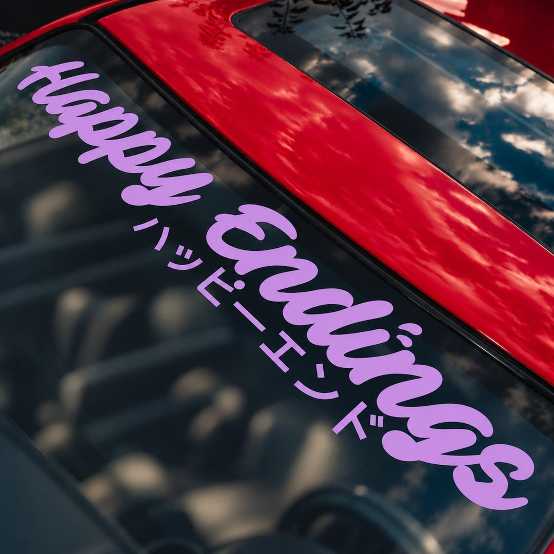 Happy Endings decal in English and Japanese script on a red car windshield.
