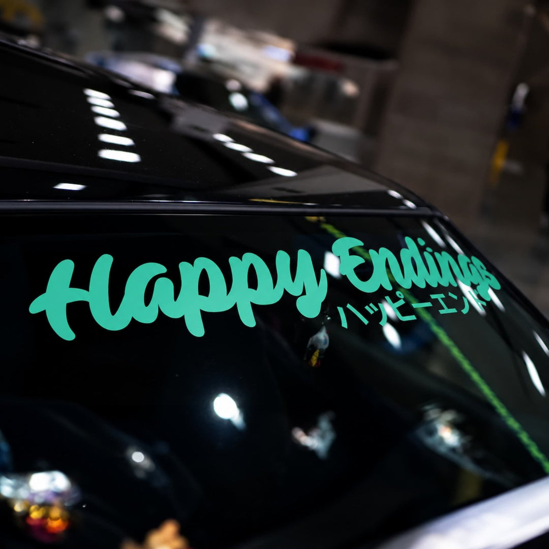 Teal Happy Endings decal with Japanese text on a cars rear window.