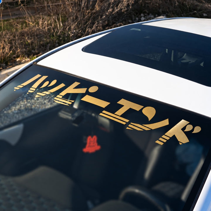 White car windshield with gold Japanese text decal.