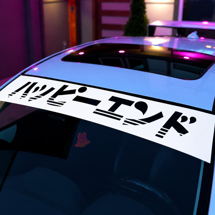 Car windshield banner with the Japanese text Happy End in black stylized lettering.