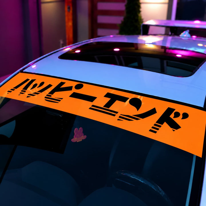 Orange windshield banner with Japanese text reading Happy End on a white car.