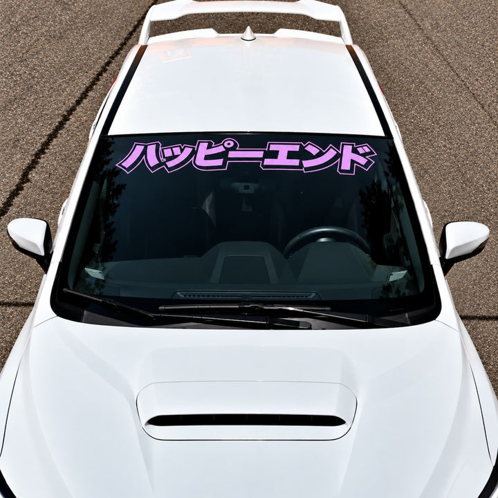 White car with a pink Japanese text decal on the windshield.
