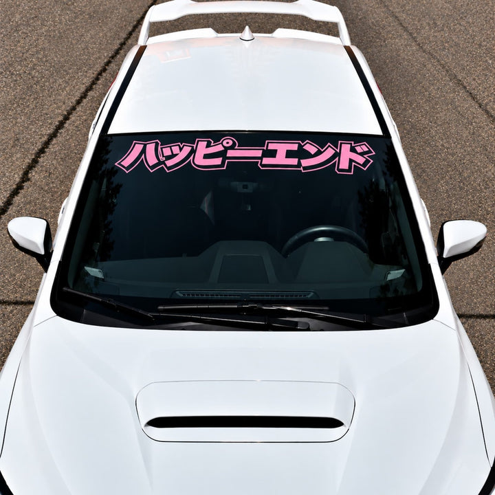 White car with a pink Japanese text decal on the windshield.