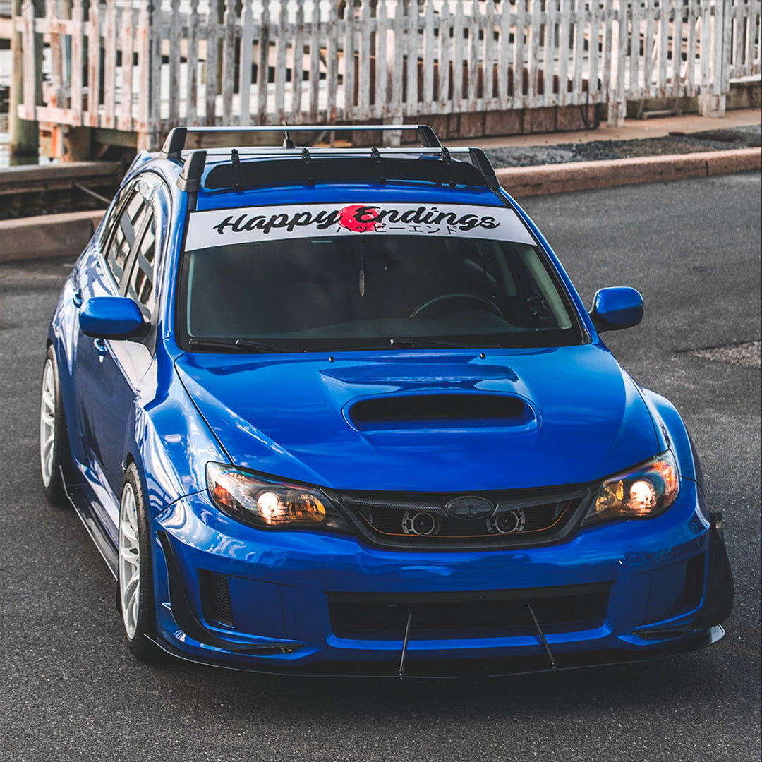 Blue car with 'Happy Endings' banner on a road