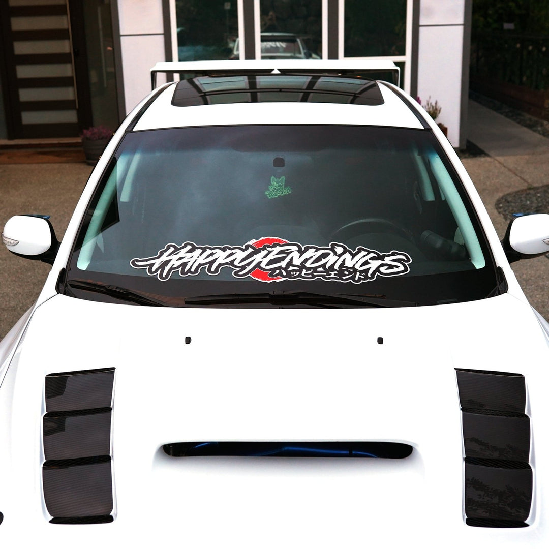 White car with a Happy Endings decal on the windshield.