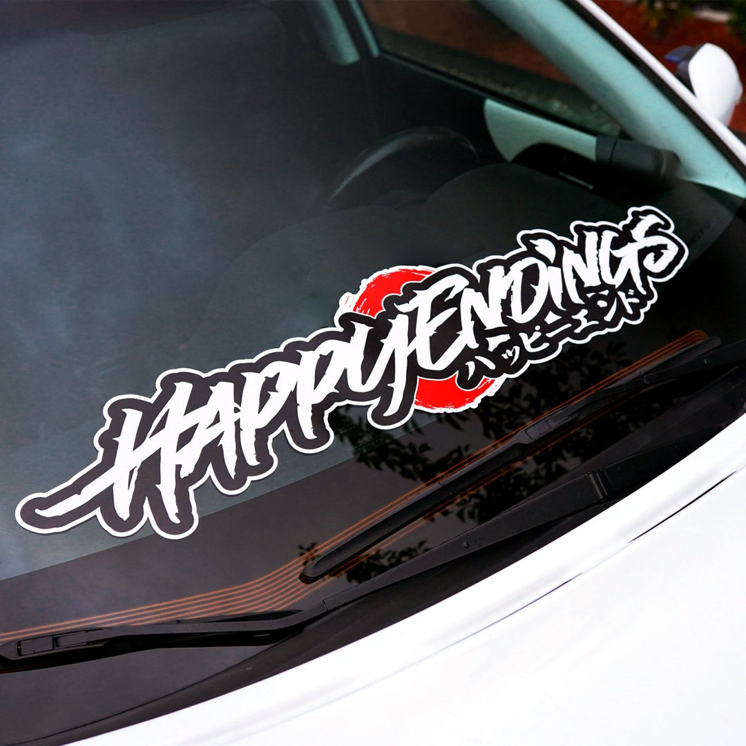 Car windshield decal reading HAPPY ENDINGS in stylized script over a red circle.