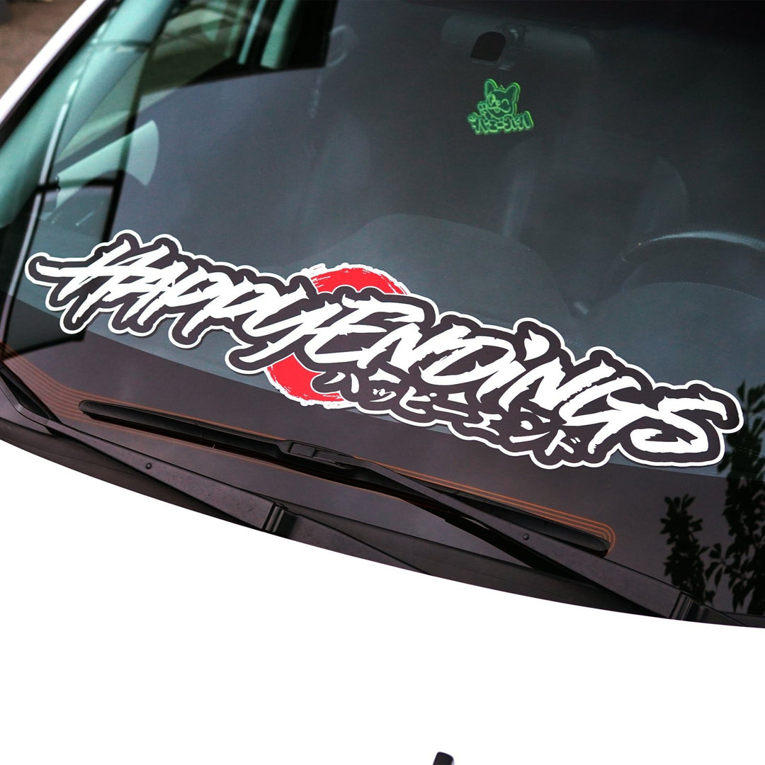 Car windshield decal reading HAPPY ENDINGS in stylized script over a red circle.