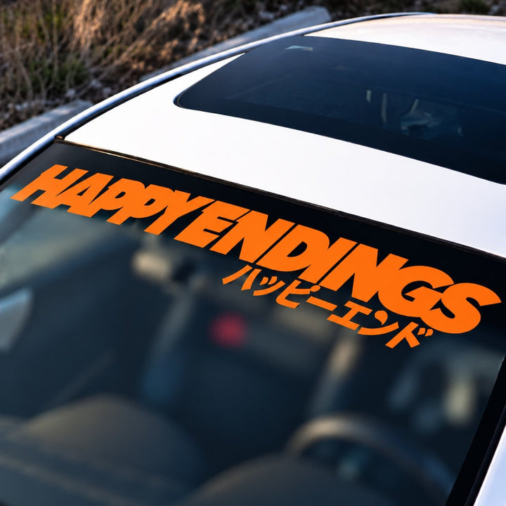 Car windshield decal reading HAPPY ENDINGS in English and Japanese.