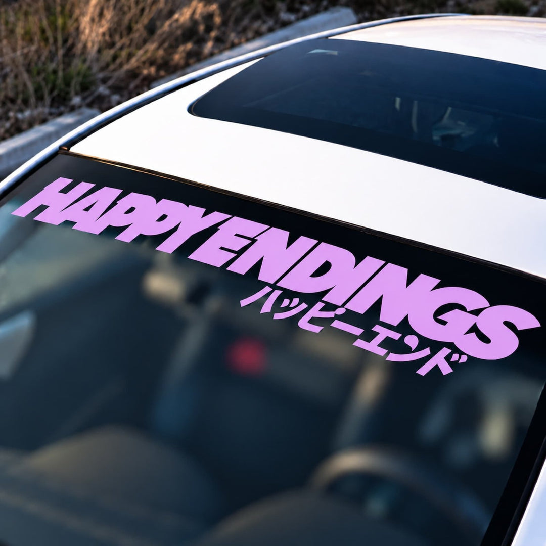 Pink HAPPY ENDINGS text in English and Japanese on a car windshield banner.