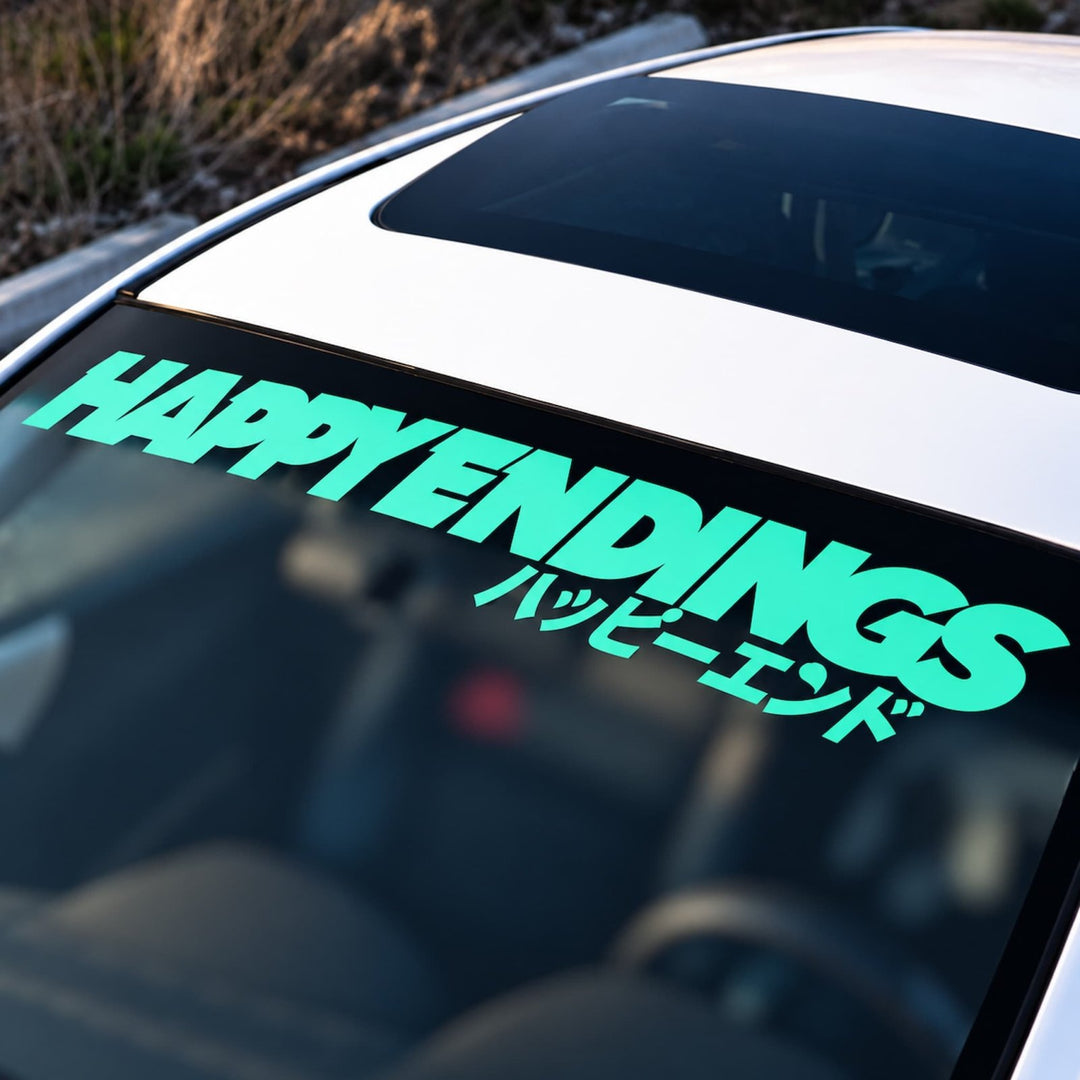 Light green HAPPY ENDINGS text in English and Japanese on a car windshield banner.
