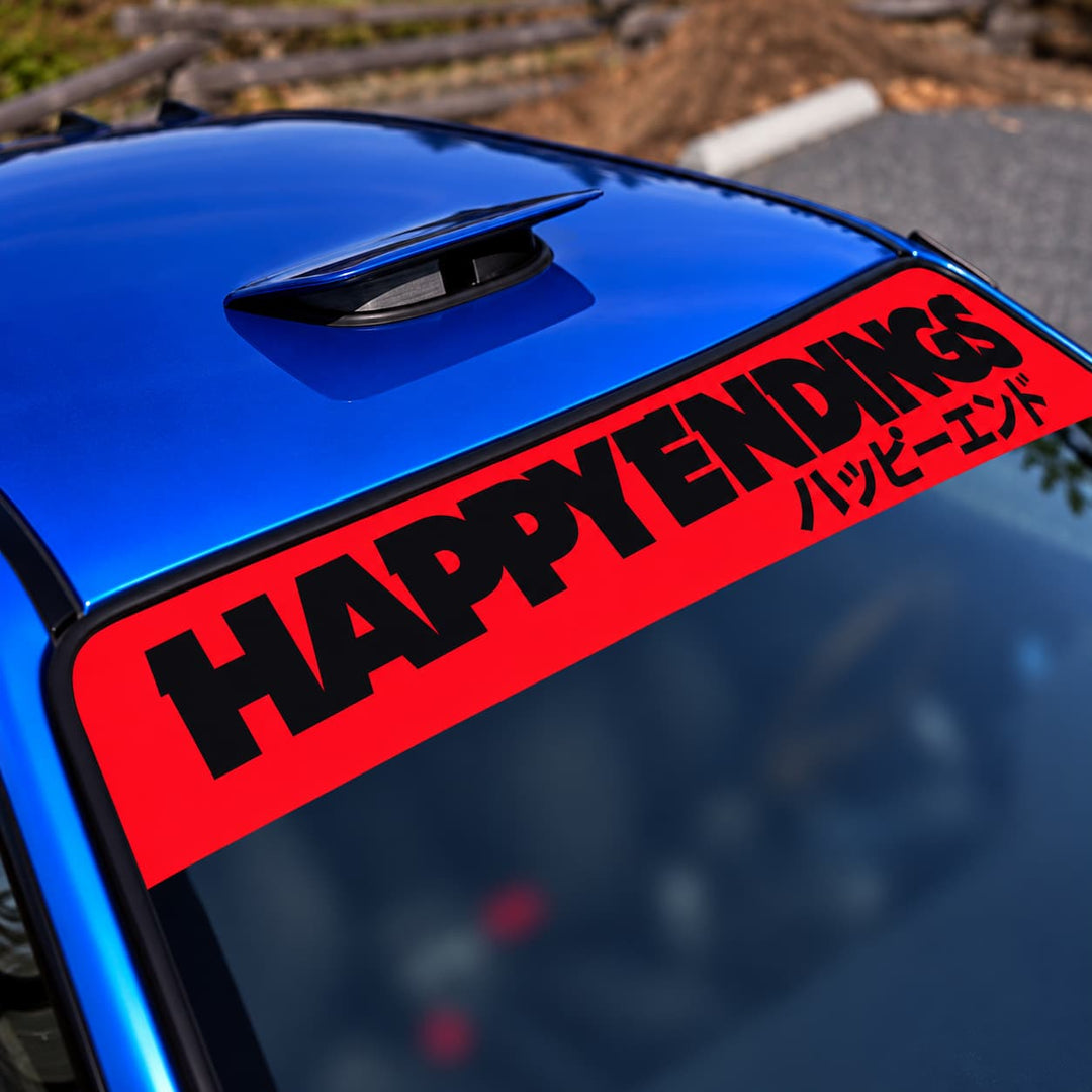 Red car windshield banner reads HAPPY ENDINGS with Japanese text on a blue car.