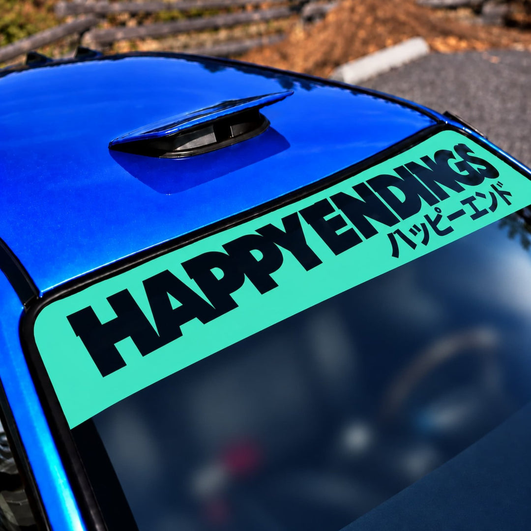 Blue car windshield with a teal banner reading HAPPY ENDINGS in English and Japanese.
